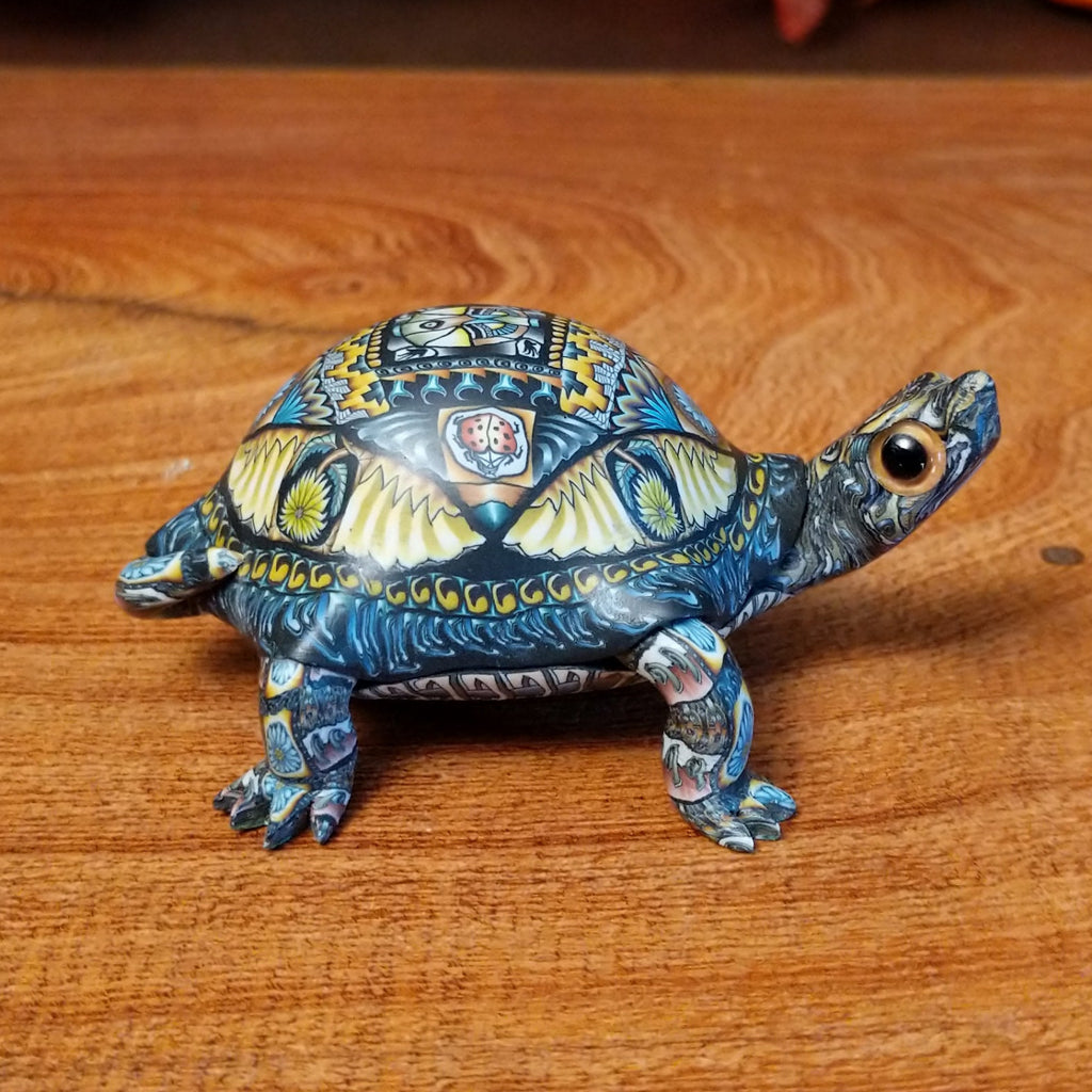 Polymer clay used to create a detailed box turtle with vibrant insect and floral motifs.