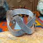 Wide silver cuff by Ryan Sanchez with interwoven textured bands and open braided design.