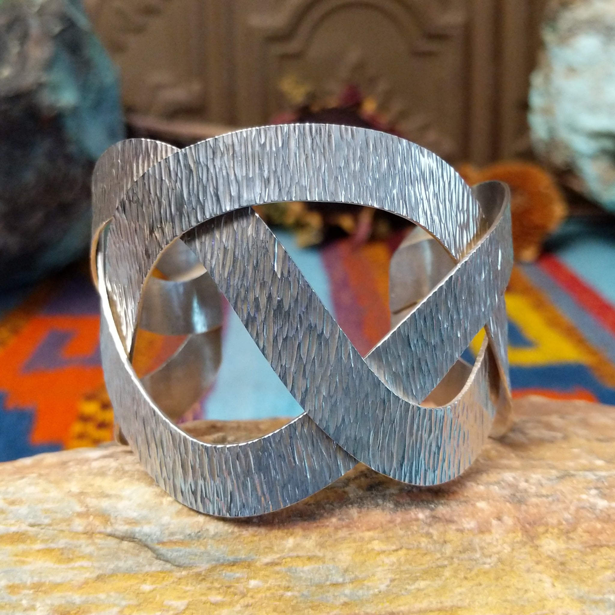 Wide silver cuff by Ryan Sanchez with interwoven textured bands and open braided design.