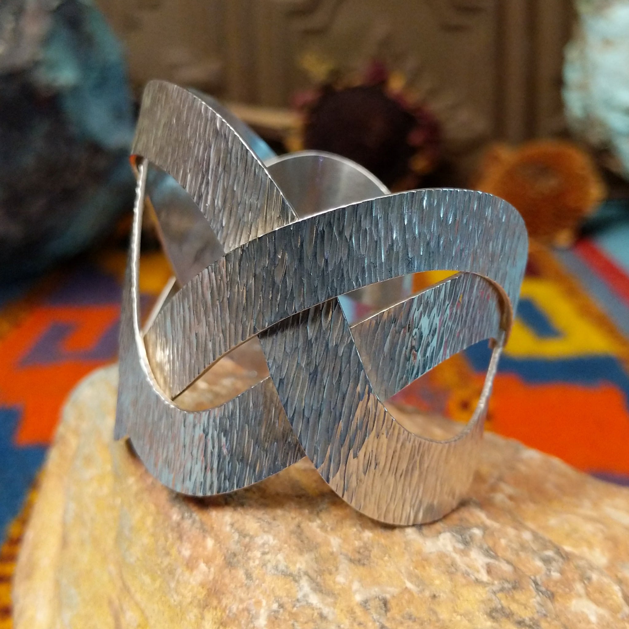 Wide silver cuff by Ryan Sanchez with interwoven textured bands and open braided design.