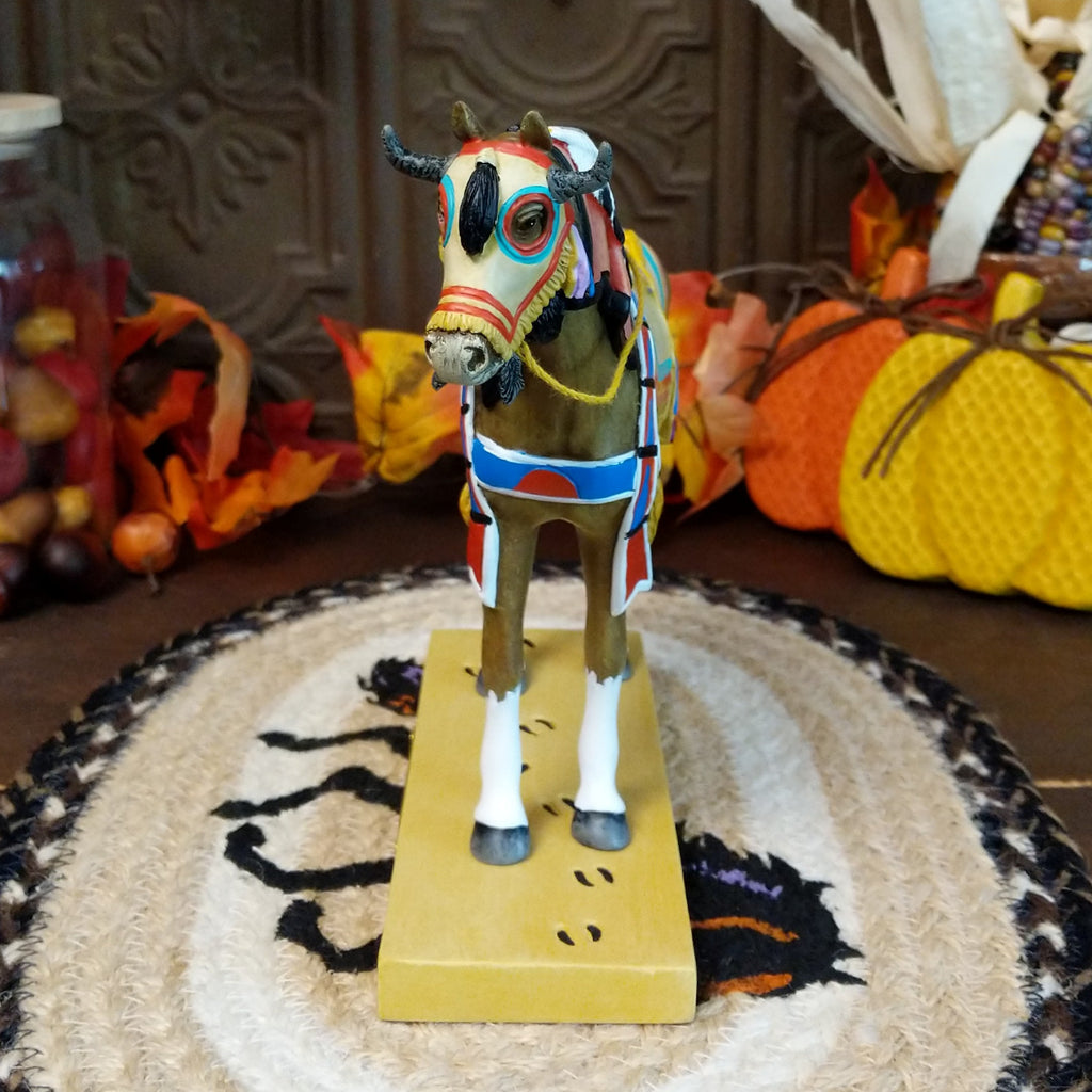Resin pony painted brown with white accents featuring a horned face shield and colorful tack.