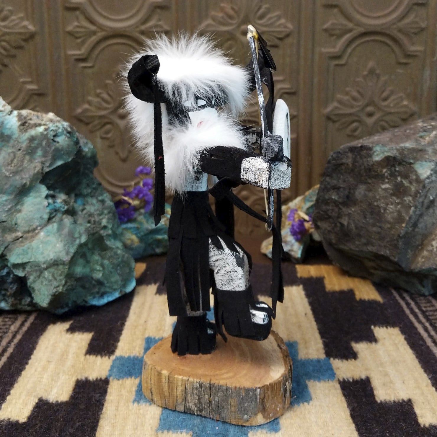 Navajo-made Buffalo Warrior kachina doll by M. C. with black garments, white fur collar, bow and arrow, and painted shield.