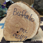 Underside of M. C. buffalo kachina doll showing handwritten signature and label on wood base.