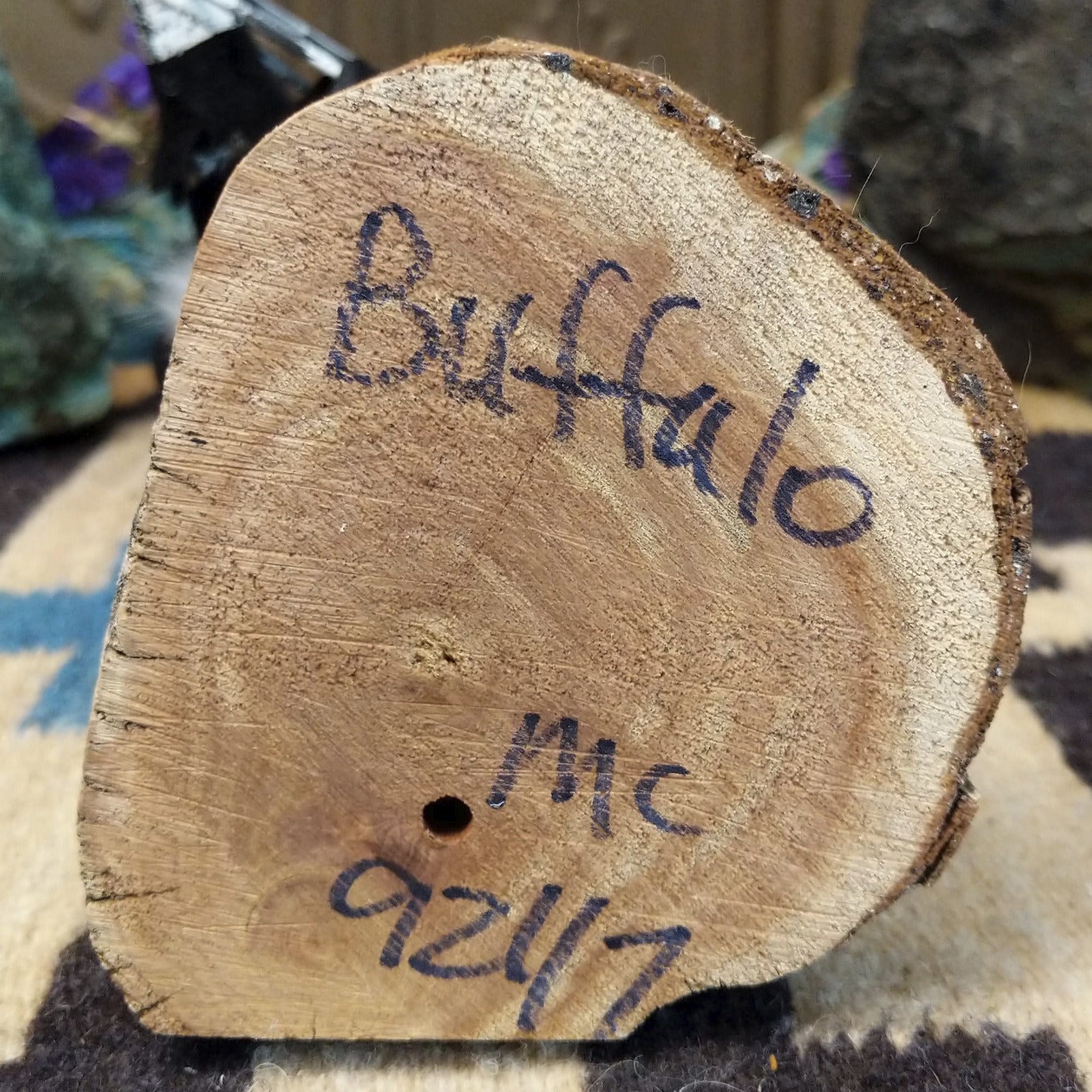 Underside of M. C. buffalo kachina doll showing handwritten signature and label on wood base.