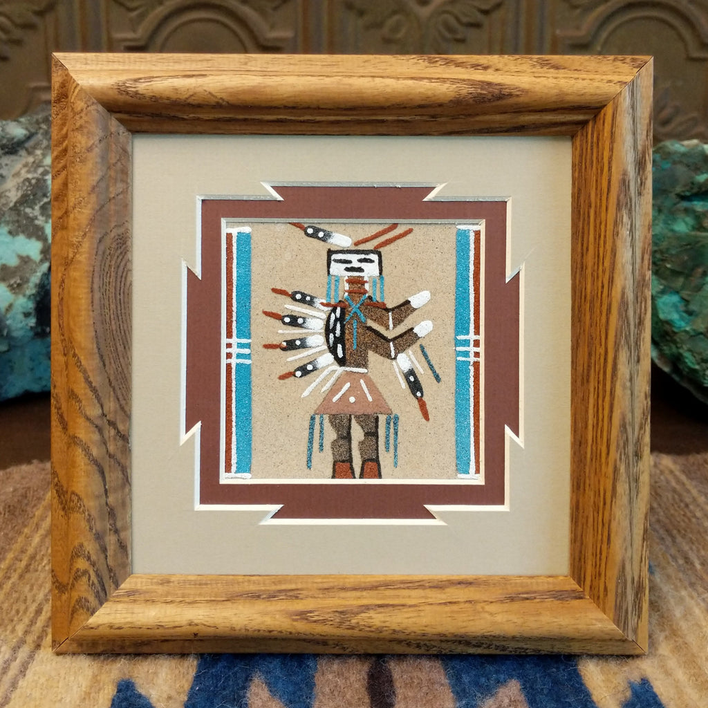 Sand painting of a buffalo warrior motif with a wooden frame.
