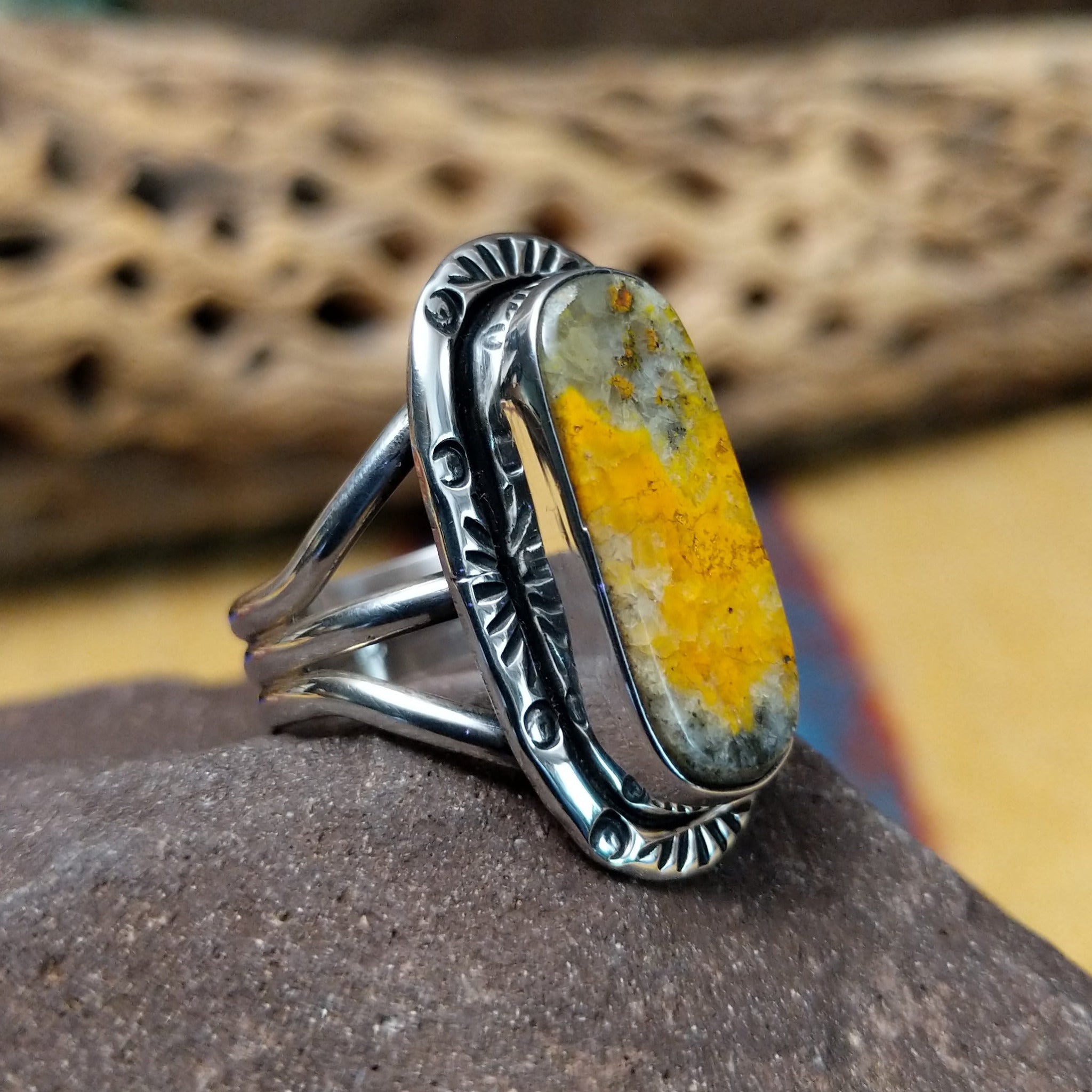 Bumblebee jasper capsule ring by Terry Wood, featuring a capsule-shaped bumblebee jasper stone with natural yellow, orange, black, and gray patterns set in a handcrafted sterling silver band.  Side view.