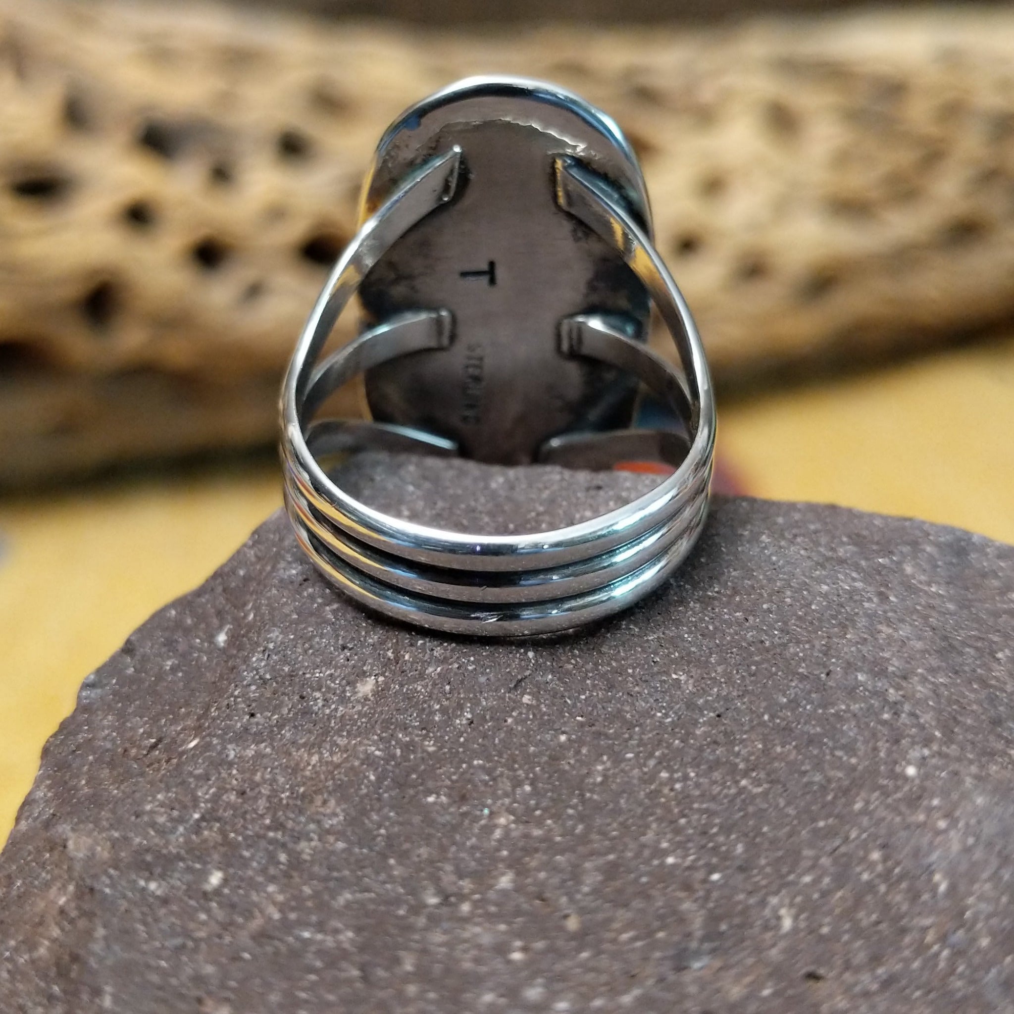 Bumblebee jasper capsule ring by Terry Wood, featuring a capsule-shaped bumblebee jasper stone with natural yellow, orange, black, and gray patterns set in a handcrafted sterling silver band.  Underside view.