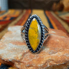 This striking Bumblebee Jasper Navette Ring by Amory Begay features an elongated golden-yellow stone with natural matrix, surrounded by a scalloped silver border and an open split-shank band.