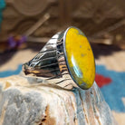 Sterling silver ring with bumblebee jasper set in an oval bezel and ornate stamping on the band.