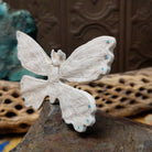 Butterfly Zuni fetish carving by Fitz Kiyite in pale stone with engraved wings and turquoise inlay accents along the wing edges.