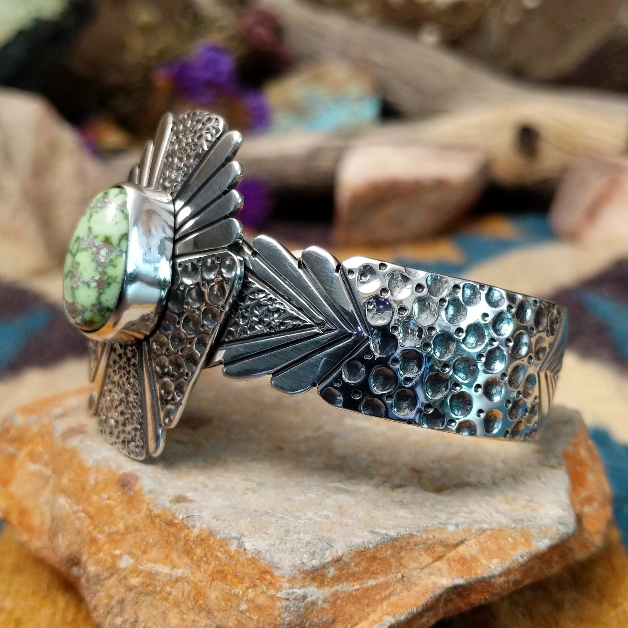 Handcrafted sterling silver shield cuff by Benjamin Piaso featuring an oval Carico Lake turquoise cabochon with ornate silver beadwork, scroll accents, blossom details, and an openwork design; side view.