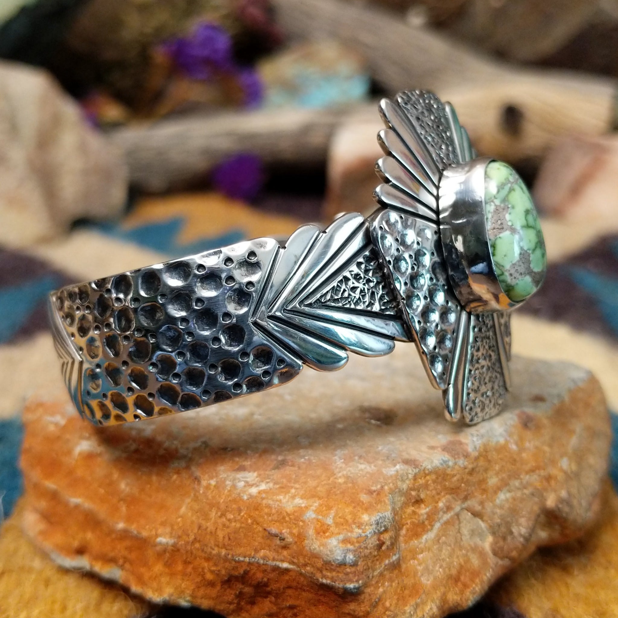 Handcrafted sterling silver shield cuff by Benjamin Piaso featuring an oval Carico Lake turquoise cabochon with ornate silver beadwork, scroll accents, blossom details, and an openwork design; side view.