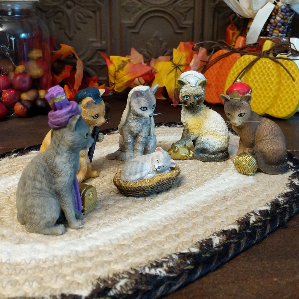 Resin cats creating a nativity scene in various colors and accents.
