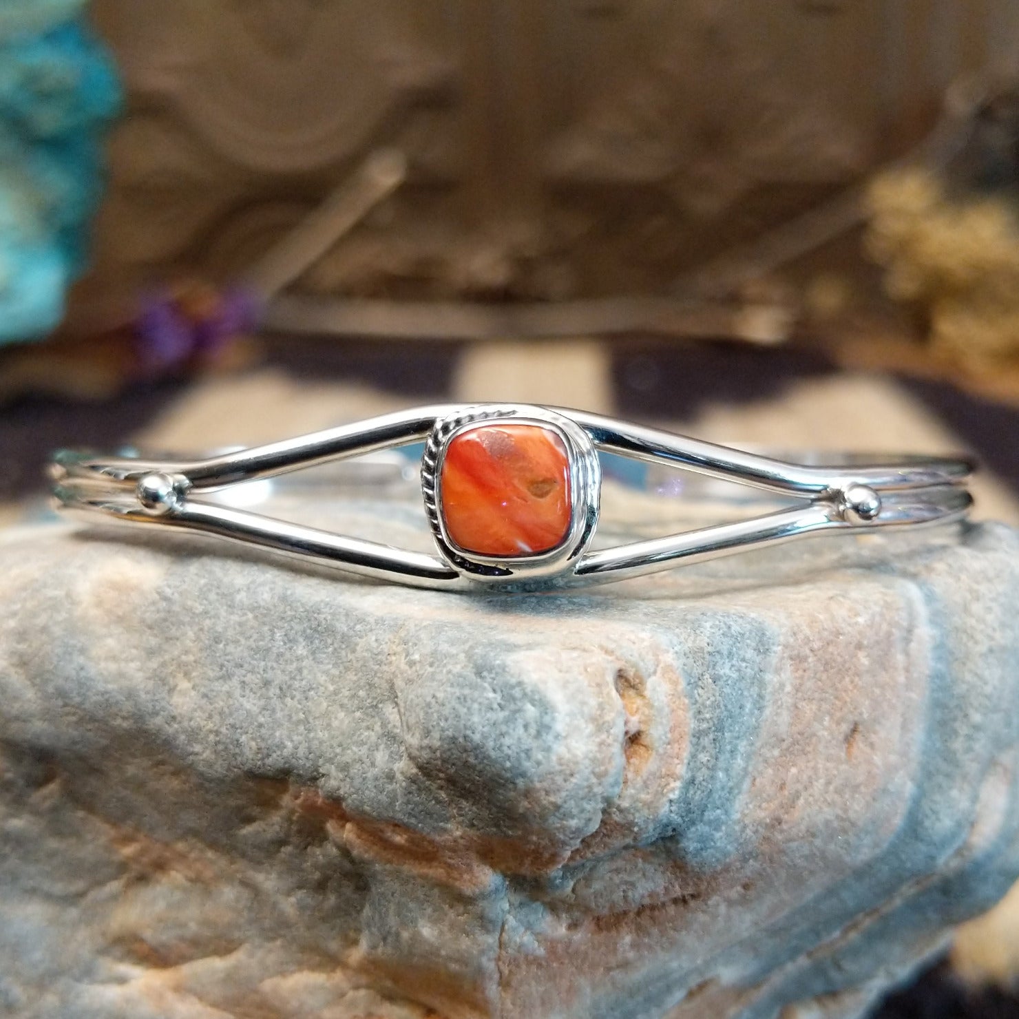 Sterling silver cuff bracelet with red spiny oyster shell set in a rounded-square bezel, framed by twisted rope accents.