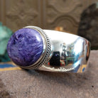 Sterling silver cuff featuring an oval charoite stone framed by a twisted rope bezel.