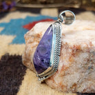 Sterling silver pendant with charoite set in a shield-shaped bezel, framed by twisted rope and dotted accents.