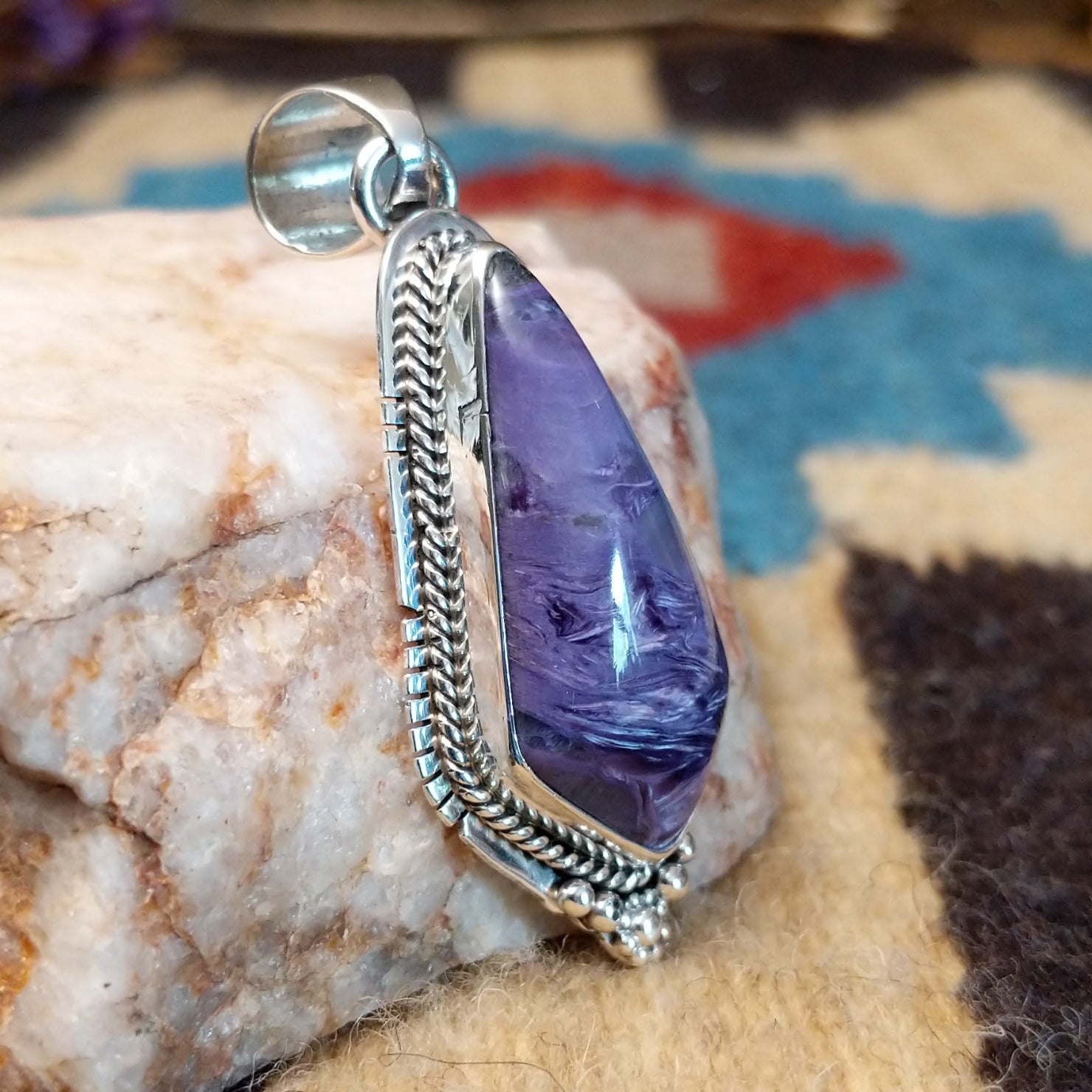 Sterling silver pendant with charoite set in a shield-shaped bezel, framed by twisted rope and dotted accents.