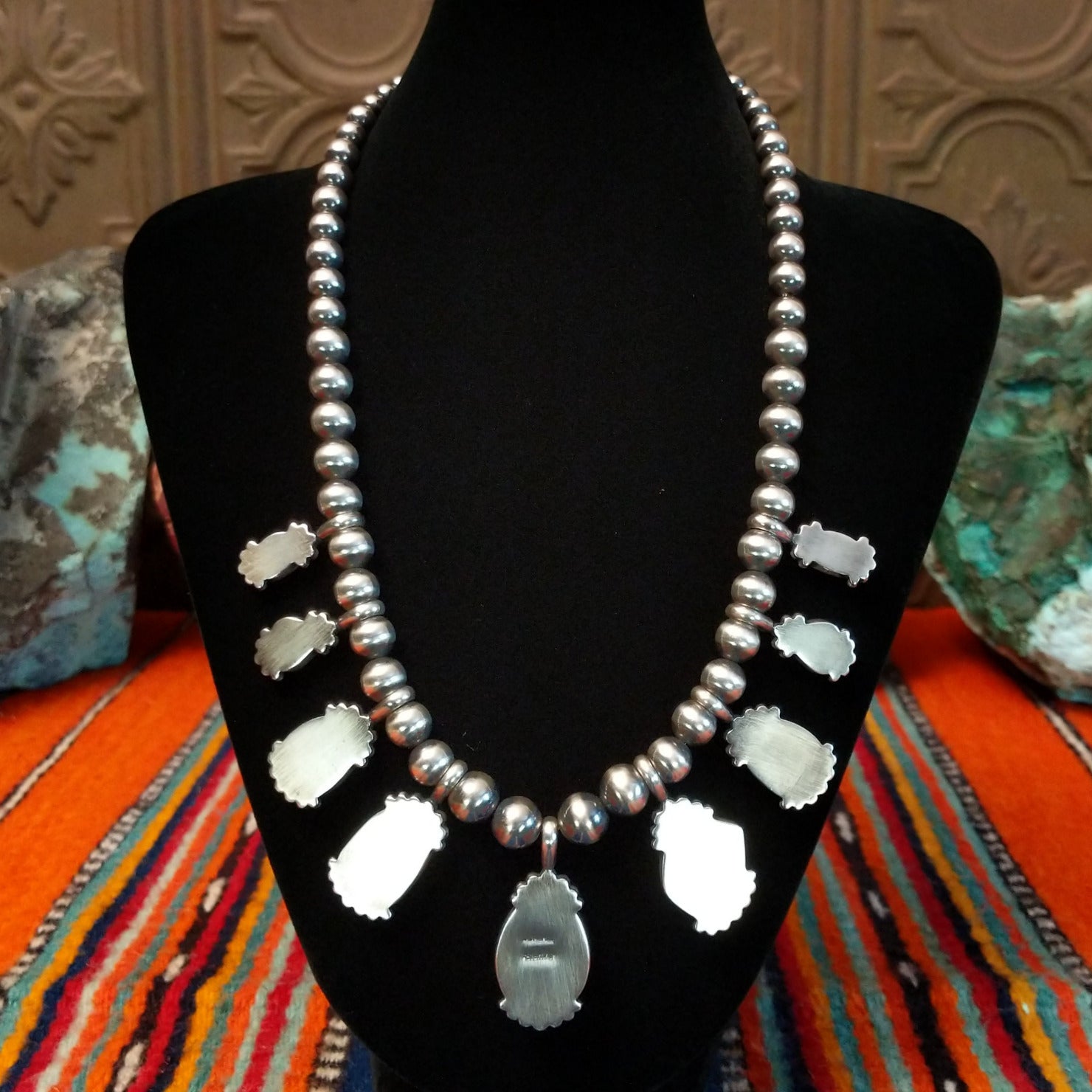 The smooth sterling silver bezels and beaded chain of the necklace.