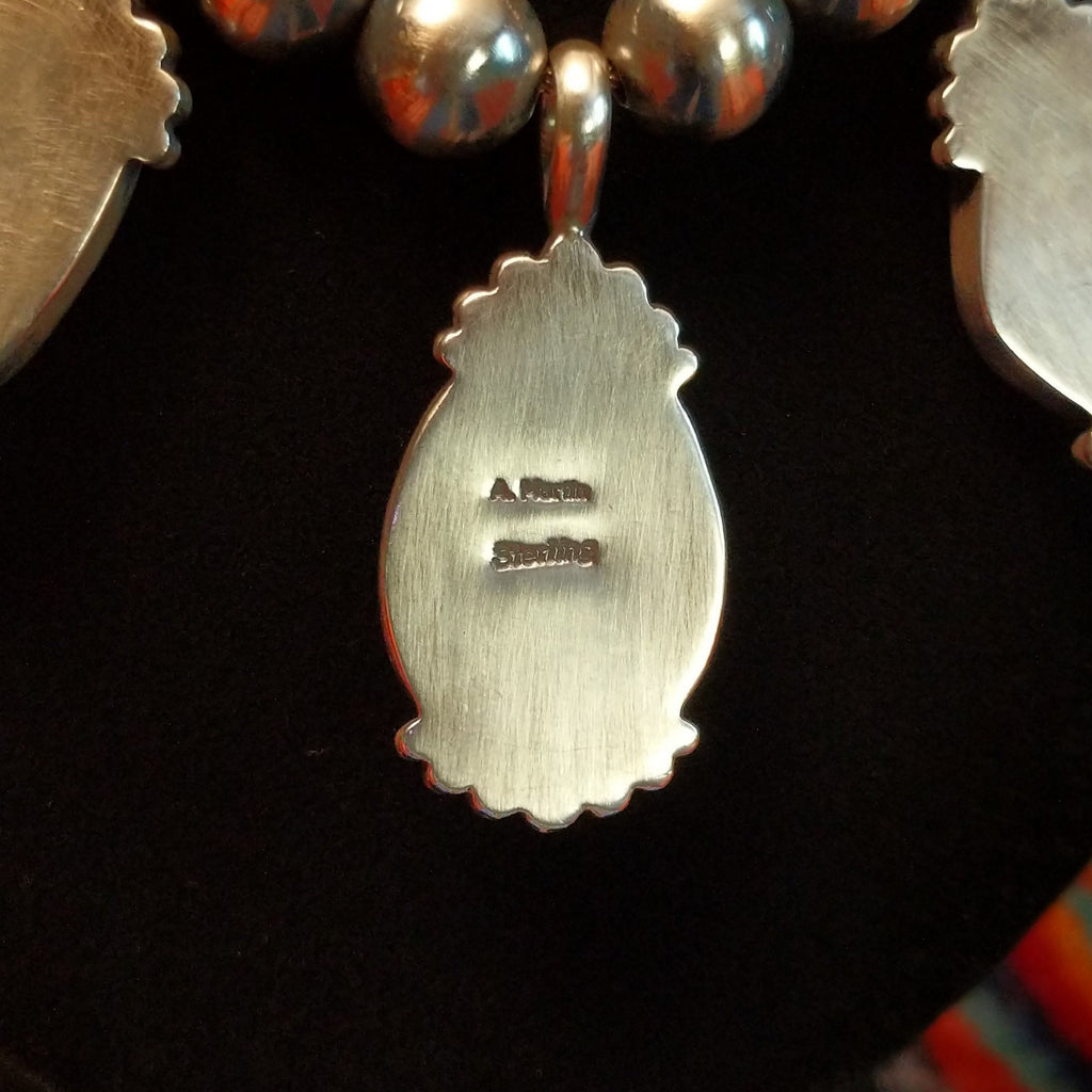 The artisan's signature found on the back of the pendant.