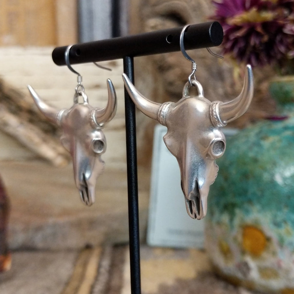 Metal bull skull dangle earrings with curved horns.