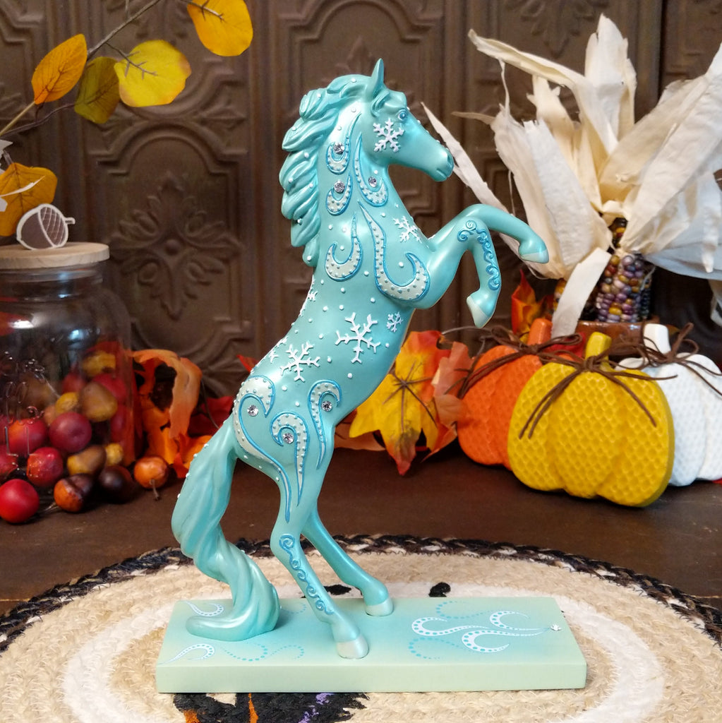 Resin pony painted a shimmering teal with squalls and snowflakes decorating its body.
