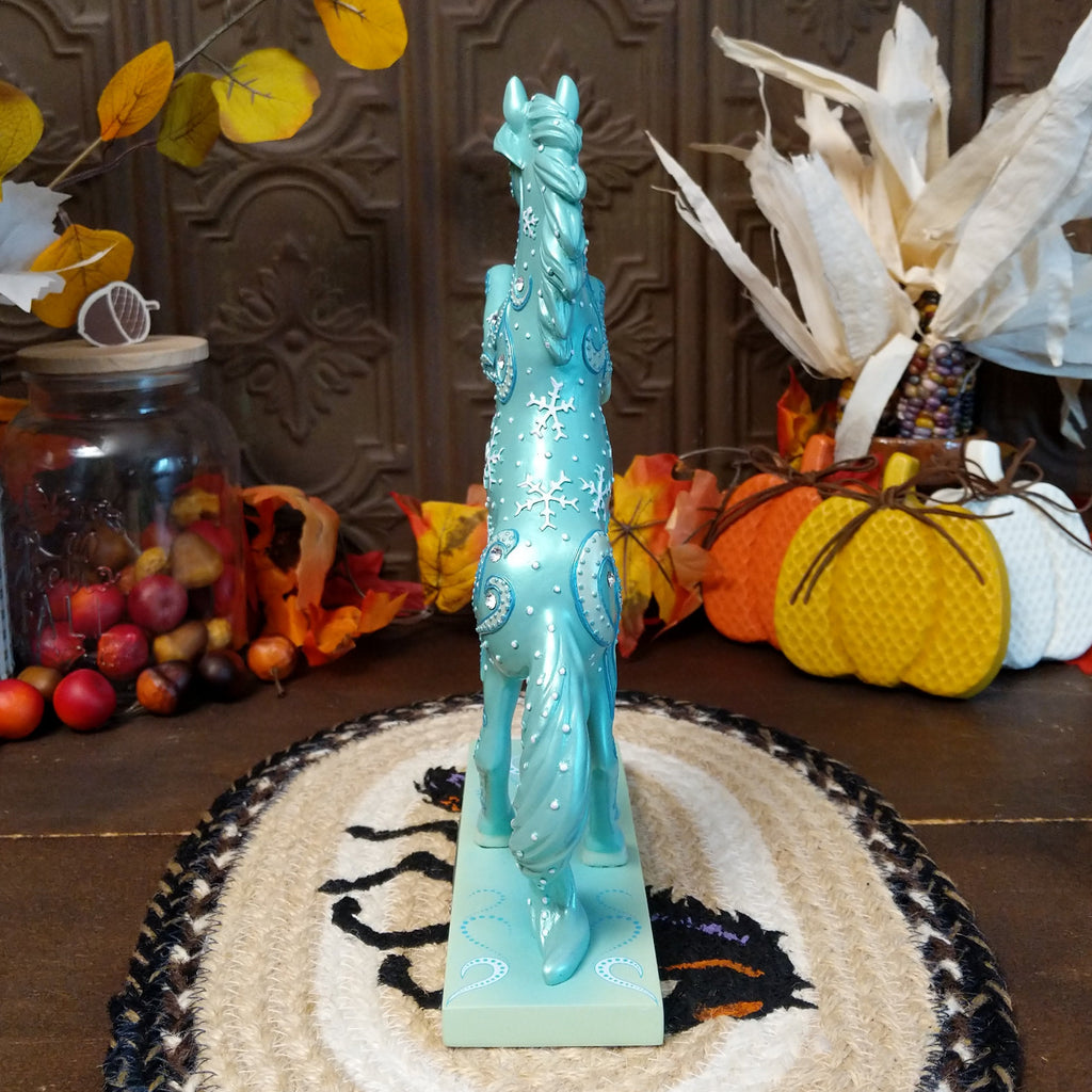 Resin pony painted a shimmering teal with squalls and snowflakes decorating its body.