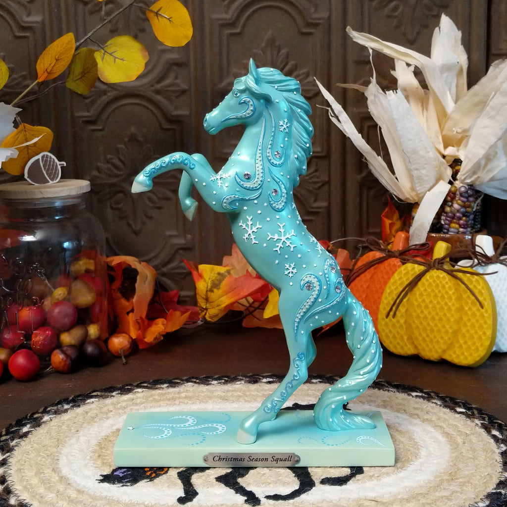 Resin pony painted a shimmering teal with squalls and snowflakes decorating its body.