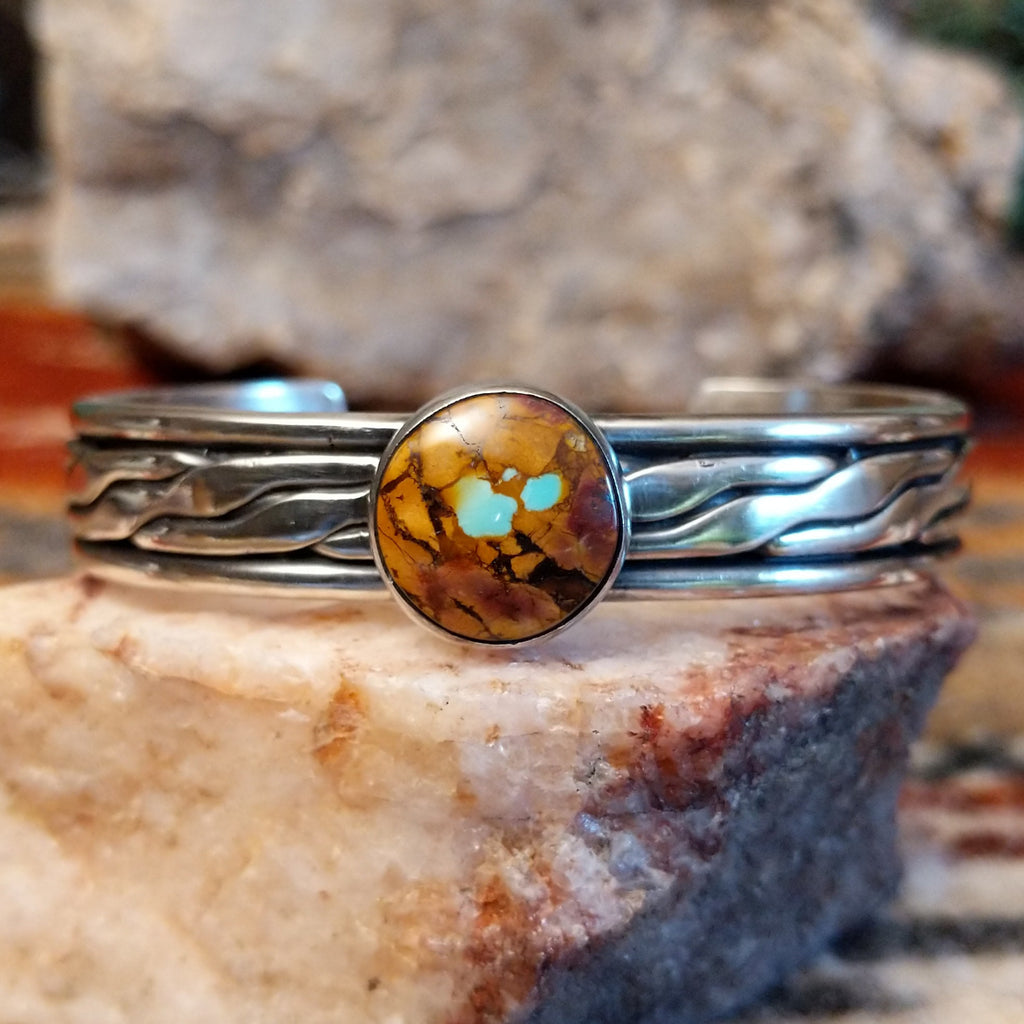 Silver bracelet with a circular stone of Boulder Turquoise on a silver surface