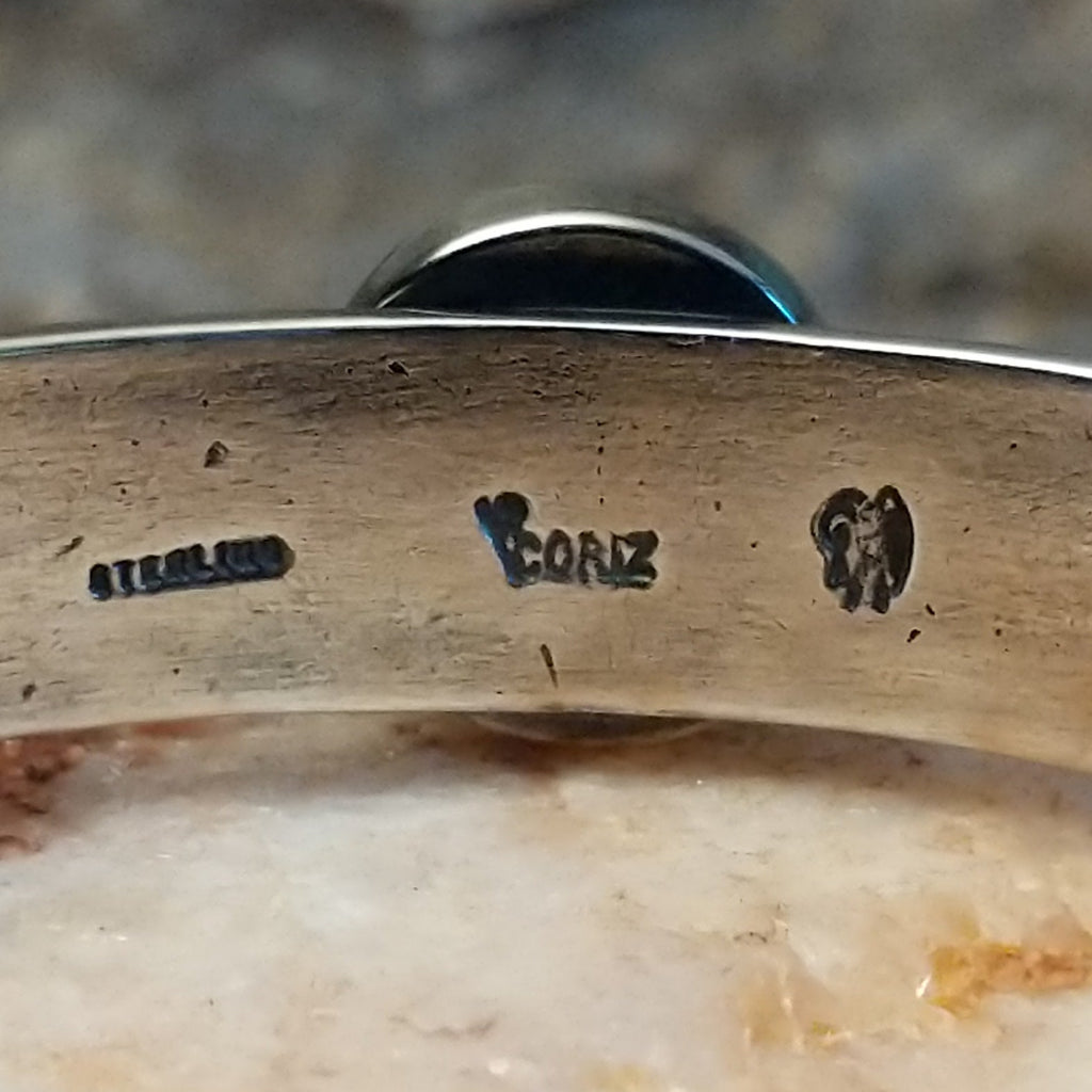 Close-up of back of bracelet with 'Coriz' hallmark and 'Sterling' marking on a textured surface.