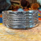 Wide silver cuff by Charlene and Robert Little with layered rows of sunburst, diamond, and circle stampwork.