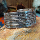 Wide silver cuff by Charlene and Robert Little with layered rows of sunburst, diamond, and circle stampwork.
