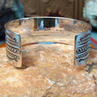 Wide silver cuff by Charlene and Robert Little with layered rows of sunburst, diamond, and circle stampwork.