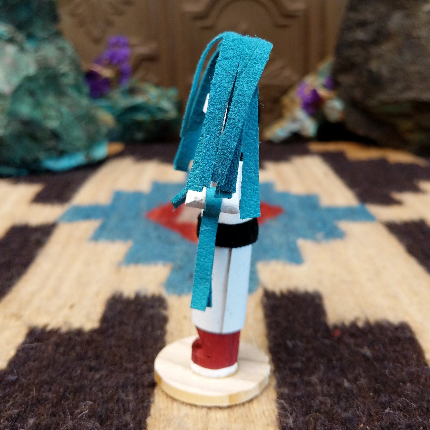 Mini clown kachina by Rosalind Grey with turquoise pigtails, white face, black striped body, and white geometric-patterned garment.