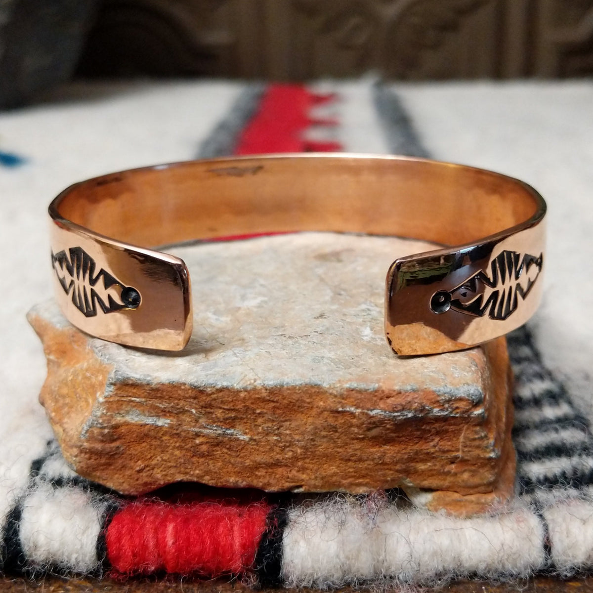 Copper and silver cuff by Robert Little featuring a repeating stamped bush-inspired pattern with oxidized detailing, framed by polished copper borders; underside view.