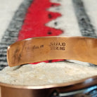 This Copper & Silver Feather Cuff by Robert Little features polished copper borders and a sterling silver center decorated with detailed feather motifs, curved accents, and dark oxidized stamping; artisan and Sterling Silver stamp.