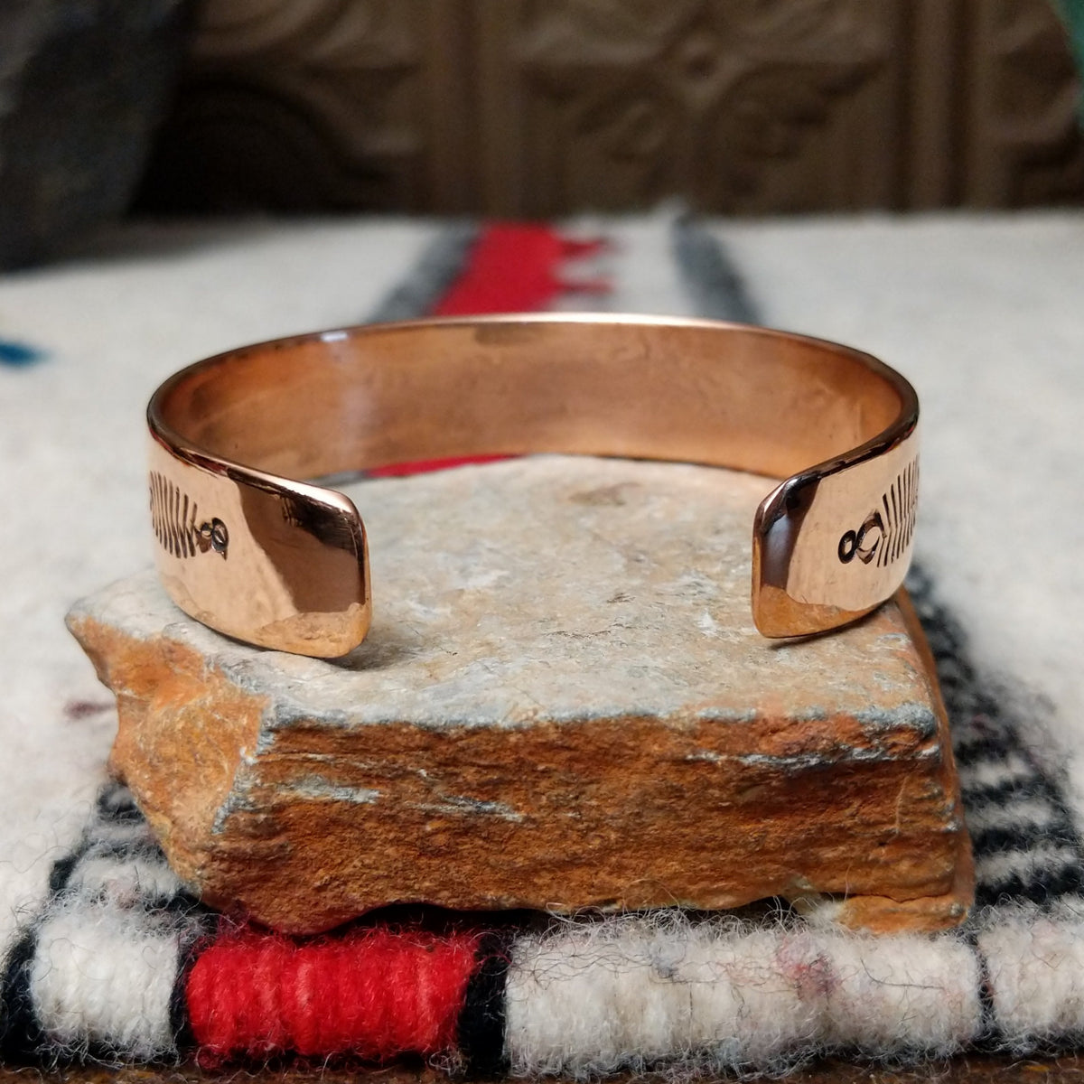 This Copper & Silver Cuff by Robert Little features polished copper borders, a sterling silver center, repeating scalloped hand-stamped motifs, fine textured edges, and dark oxidized accents; underside view.