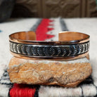 Copper and silver cuff by Robert Little featuring a repeating oxidized hand-stamped design across the silver center, framed by polished copper borders.