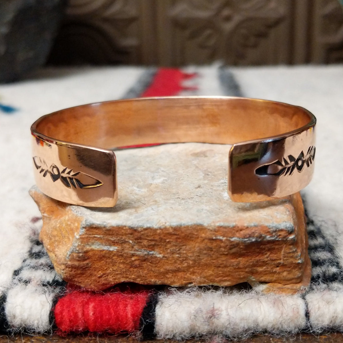 Copper and silver cuff by Robert Little featuring a repeating oxidized hand-stamped design across the silver center, framed by polished copper borders; underside view.