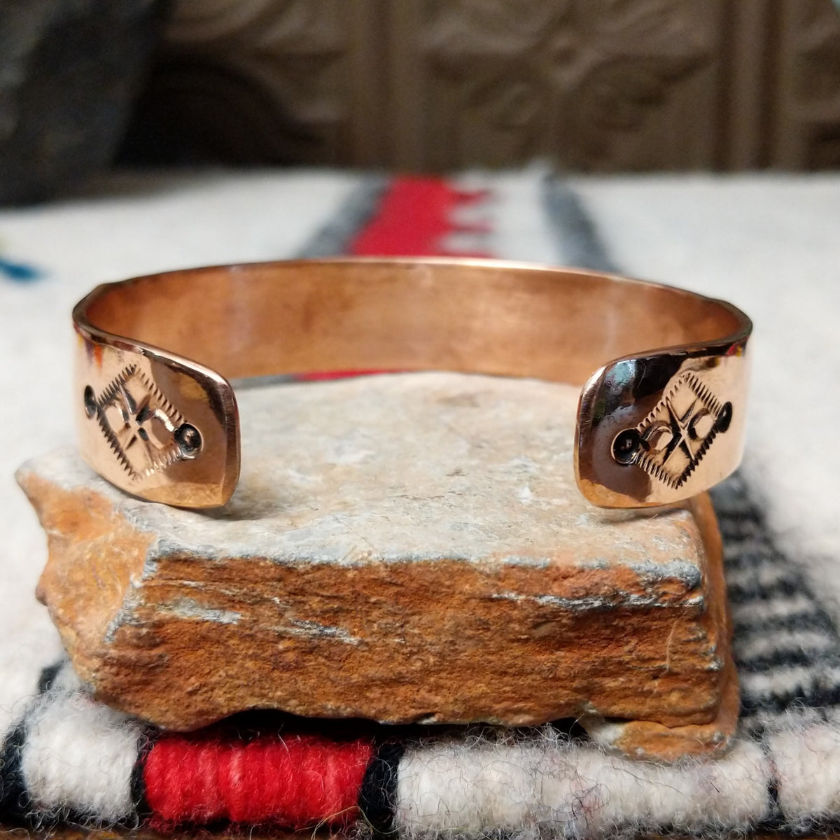 Copper and silver cuff by Robert Little featuring a repeating stamped ray design across an oxidized silver center, framed by polished copper borders; underside view.