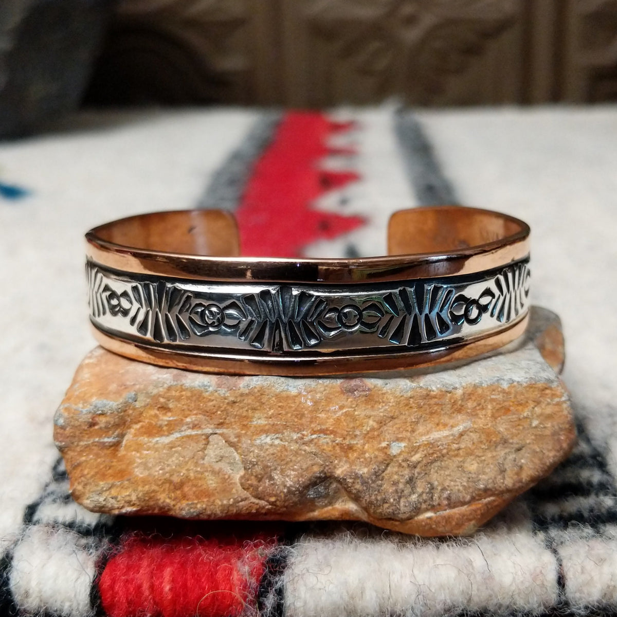 Copper and silver cuff by Robert Little featuring an intricate repeating hand-stamped geometric pattern with oxidized accents, framed by polished copper borders.