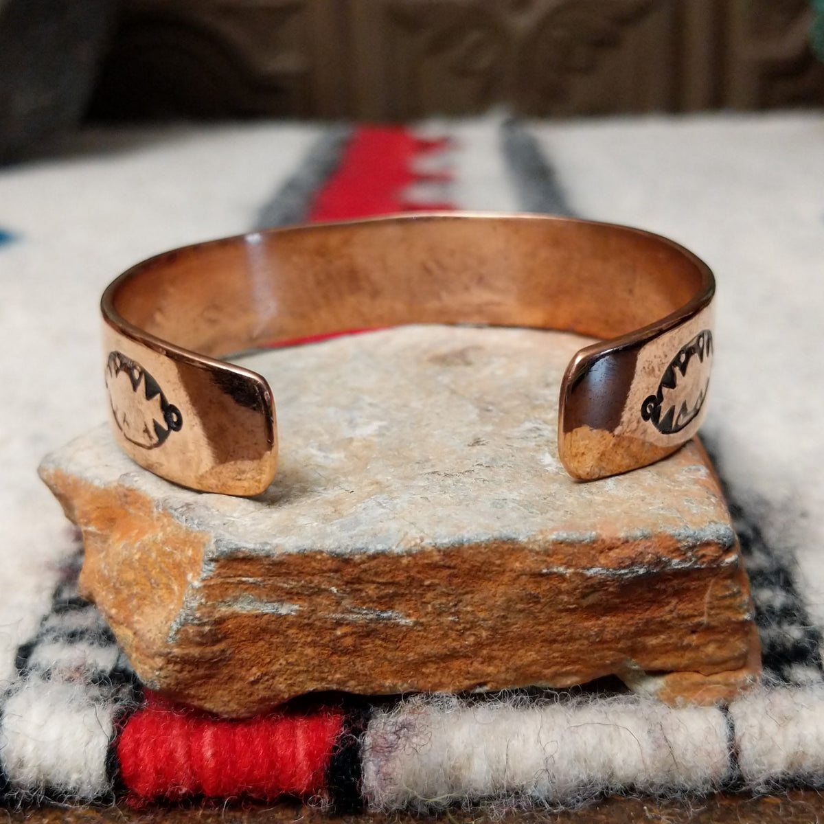 Copper and silver cuff by Robert Little featuring an intricate repeating hand-stamped geometric pattern with oxidized accents, framed by polished copper borders; underside view.