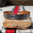 Copper and silver cuff by Robert Little featuring a repeating stepped geometric pattern in oxidized sterling silver, framed by polished copper borders.