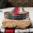 Copper and silver cuff by Robert Little featuring repeating stamped tipi-inspired geometric designs across an oxidized silver center, framed by polished copper borders.