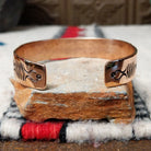 Copper and silver cuff by Robert Little featuring repeating stamped tipi-inspired geometric designs across an oxidized silver center, framed by polished copper borders; underside view.