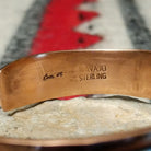 Copper and silver cuff by Robert Little featuring a repeating hand-stamped chevron or feather-inspired pattern with dark oxidized accents and polished copper borders; artisan and Sterling Silver stamp.