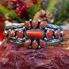 Sterling silver cuff with clusters of red coral, twisted rope accents, and scalloped stamps.