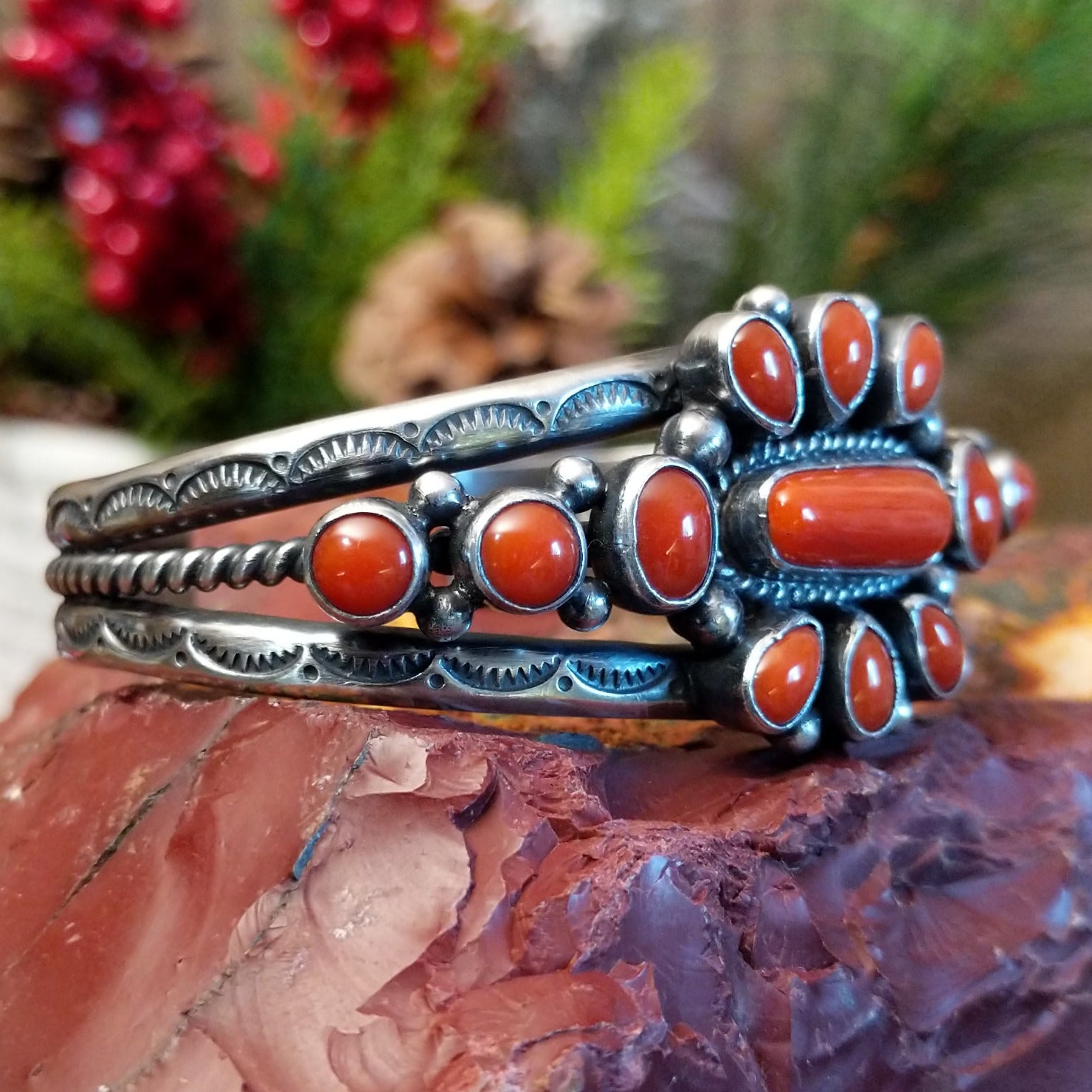 Sterling silver cuff with clusters of red coral, twisted rope accents, and scalloped stamps.