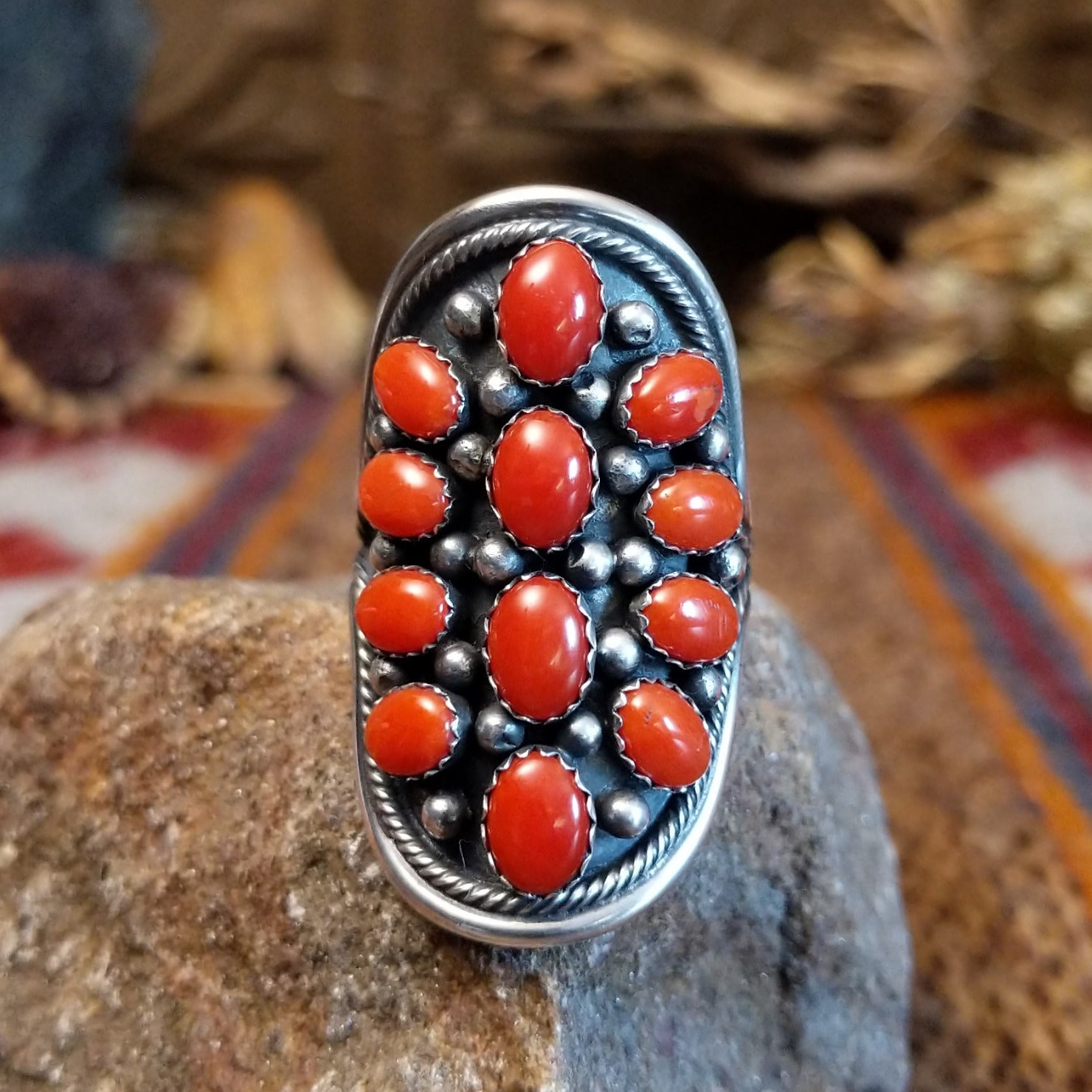 Sterling silver ring with coral set in clustered bezels, framed by intricate dot work.