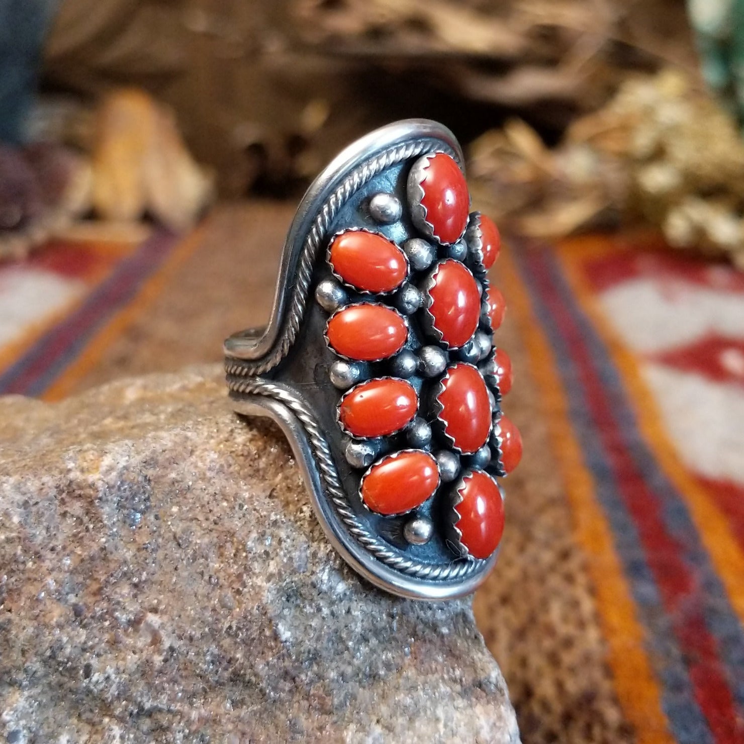 Sterling silver ring with coral set in clustered bezels, framed by intricate dot work.