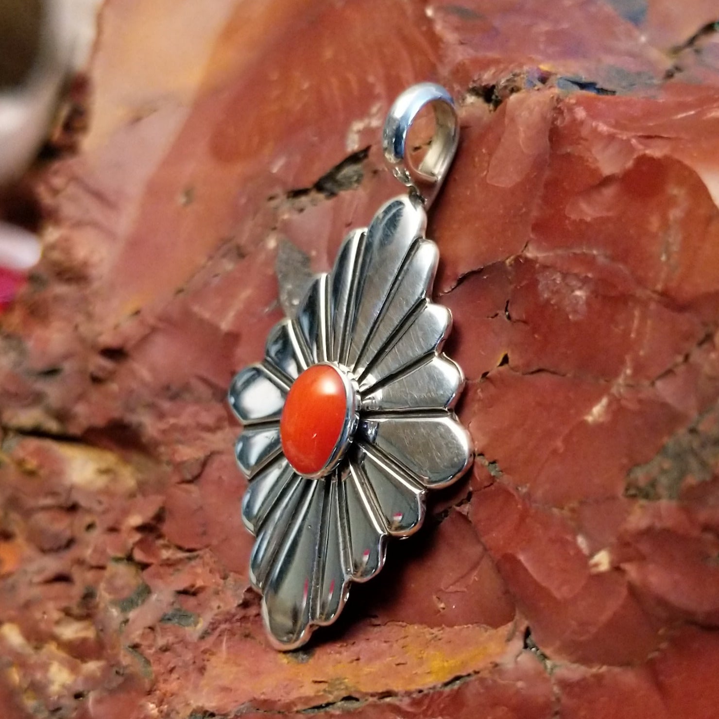 Sterling silver pendant with red coral centerpiece and diamond-shaped setting.